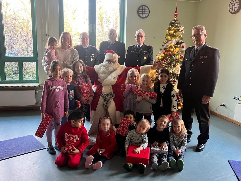 Unterender Feuerwehrkameraden helfen dem Weihnachtsmann